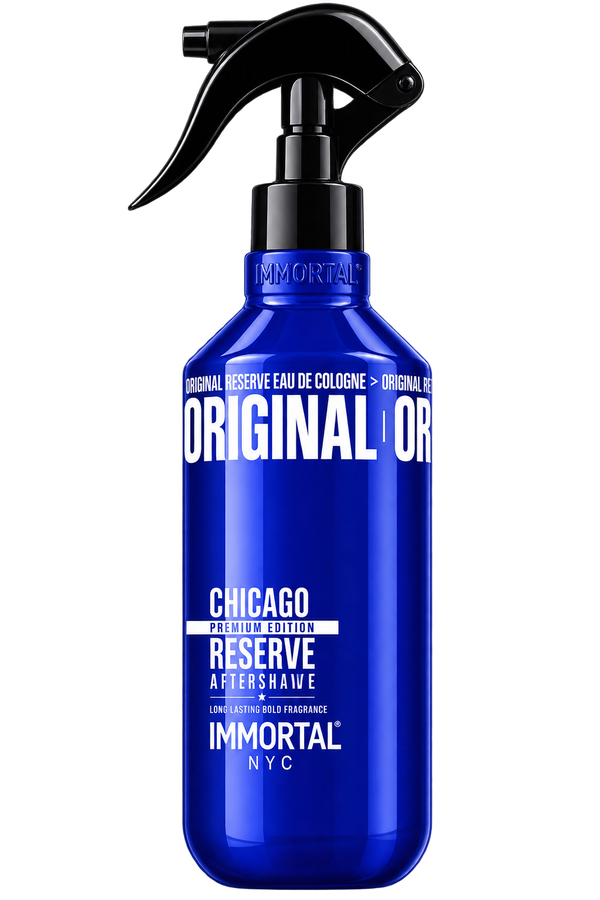 A cobalt blue spray bottle of Immortal Chicago Family Edition Reserve Aftershave with a black trigger sprayer, isolated on a white background.