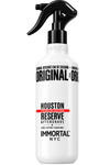 A white spray bottle of Immortal NYC Original Reserve Aftershave in the Houston scent, featuring a black trigger spray top and bold black text with a red accent stripe on the label.