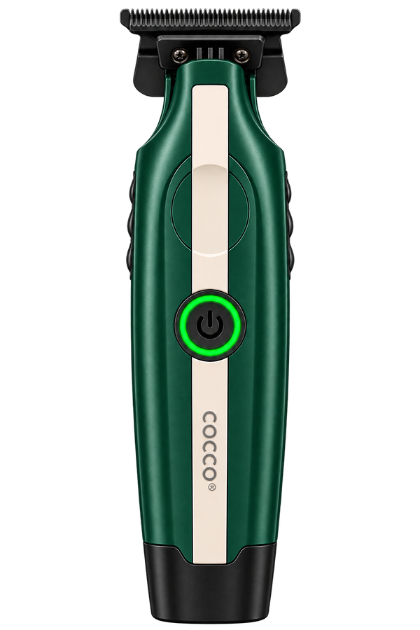 A Cocco electric hair trimmer shown from the front on a solid white background. The clipper features a dark green body with a vertical cream-colored stripe, a black power button with a glowing green ring, and a black metal cutting head.