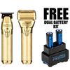 Two gold FXONE hair clippers shown on a white background, alongside a black FXONE dual battery charger and two blue batteries, with large text reading 'FREE DUAL BATTERY KIT'.