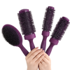Four purple hair styling brushes with dark bristles, held together by a person's hands against a solid white background.
