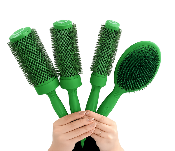 Four green hairbrushes held together by two hands against a solid white background. Three are round barrel brushes and one is an oval paddle brush, all with dense green bristles.