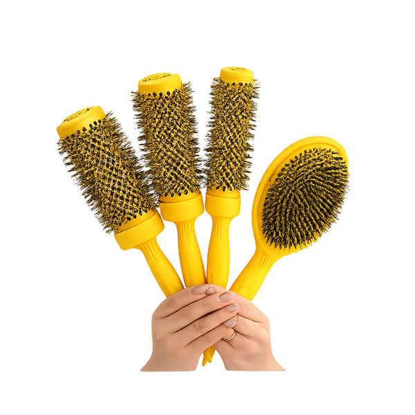 Four yellow hair styling brushes held by hands against a plain white background. Three are round barrel brushes and one is an oval paddle brush, all with dark bristles.
