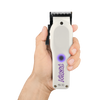 Hand holding a white hair clipper with purple branding on a white background